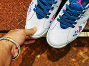Close-up of the white textured toe boxes, blue laces, and colorful abstract patterned panels on the sneakers.