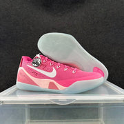 Pink and white basketball shoes shown from the side and outsole, highlighting the translucent sole and Kobe-related tongue graphic.