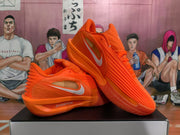 Angled product view showing a pair of orange Nike sneakers with lace-up fronts, side Swooshes, textured uppers, and orange outsoles.