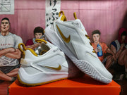 Angled view of white and gold Nike Zoom basketball shoes showing the side and patterned sole