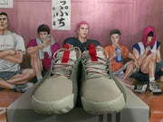 Front view of green sneakers showing cream toe panels, red-trimmed laces, and textured outsoles.
