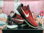 Angled view of the pair highlighting the red and black colorway, white Swoosh, and translucent outsole.