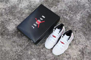Pair of white sneakers displayed beside a black Jordan shoebox.