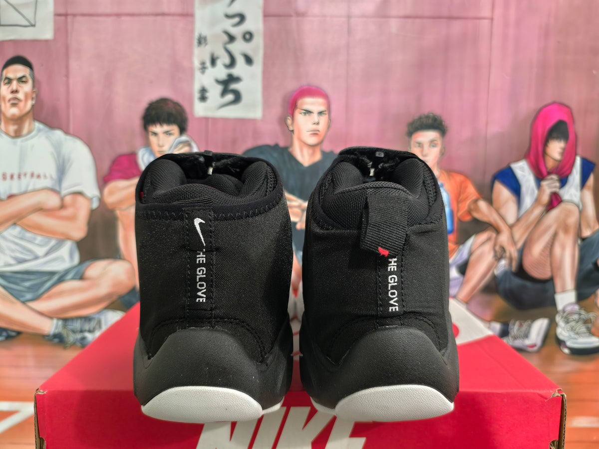 Rear view of black and white Nike sneakers showing padded collars, heel pull tabs, white outsole sections, and “THE GLOVE” heel lettering.