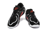 Pair of black basketball sneakers with white curved detailing, red accents, black laces, and red tongue branding.