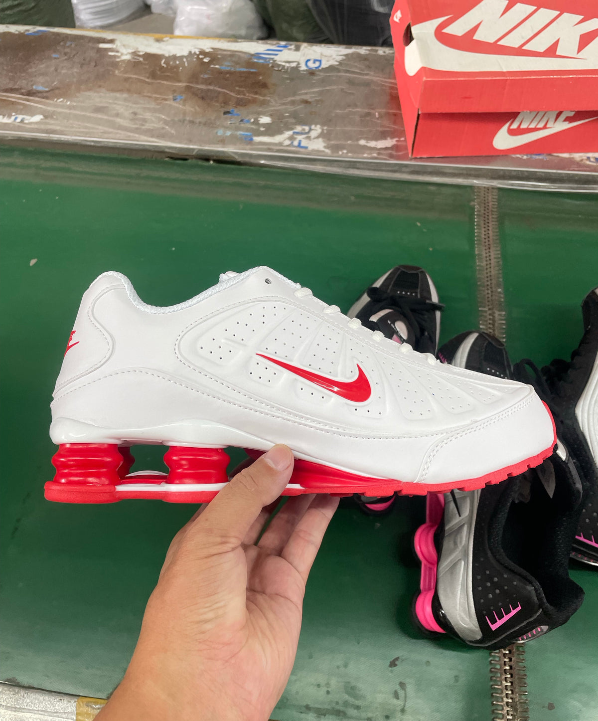 White Nike sneaker with red Swoosh, perforated side panels, and red heel columns, shown in profile.