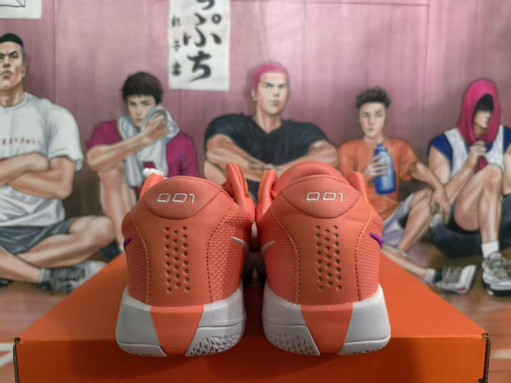 Rear view of pink Nike basketball sneakers with purple accents and white midsoles on an orange box.
