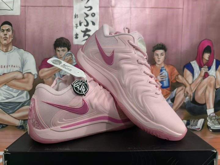Pair of pink Nike basketball-style sneakers shown from a three-quarter side angle on a black box.