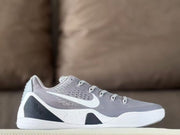 Side profile of a grey low-top basketball shoe with white and dark accent panels.