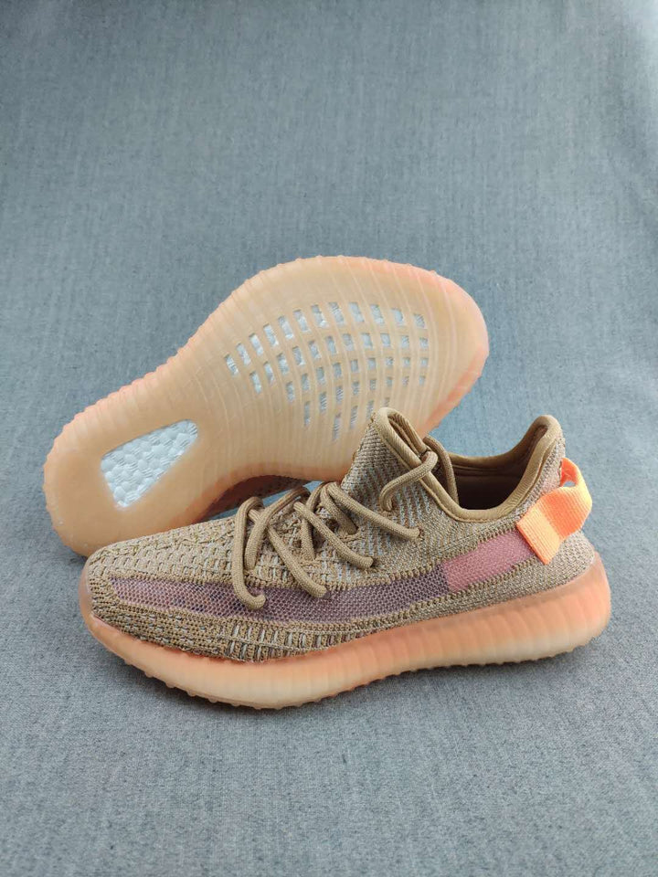 Pair of tan Yeezy 350 V2-style sneakers showing the mauve side stripe, orange heel accents, and translucent amber-toned soles.
