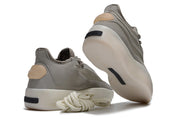 Brown-gray sneakers shown from the rear and sole, with layered uppers, cream outsoles, and coiled laces.