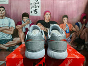 Rear view of the grey Nike sneakers showing embossed Nike branding on the heel panels and red collar accents.