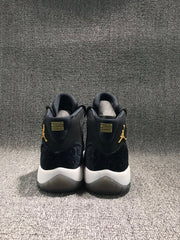 Rear view of a pair of black high-top sneakers with gold-colored branding, textured heel panels, and white midsoles.