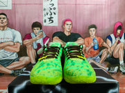 Front view of the green Nike sneaker pair with dark laces, patterned uppers, and bright neon green toe sections.
