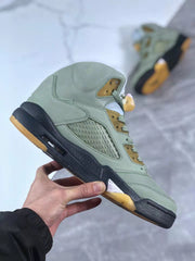 Side profile showing the green upper, mesh panel, black midsole, visible heel window, and gum-colored outsole.