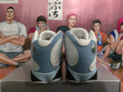 Rear view of blue-gray and white high-top sneakers showing padded collars, rounded heel details, and black outsole sections.