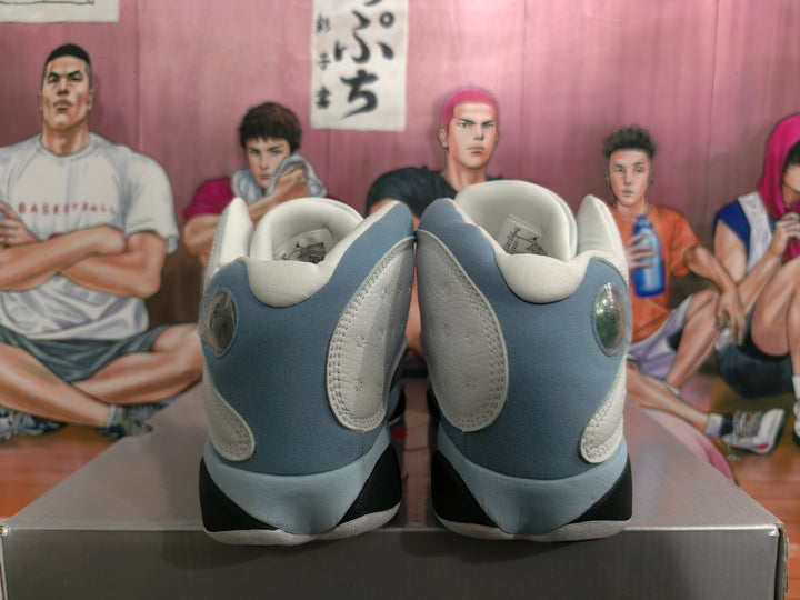 Rear view of blue-gray and white high-top sneakers showing padded collars, rounded heel details, and black outsole sections.