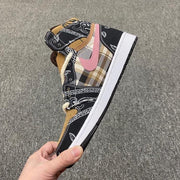 Side profile highlighting the black-and-brown patchwork upper, pink accent, cream laces, and white midsole.