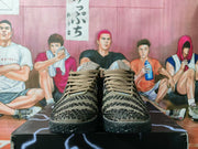 Front view of the pair of brown knit sneakers, showing the laces, padded collars, patterned uppers, and black outsoles.