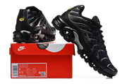Black grid-pattern Nike Air Max Plus sneakers displayed with a shoe box