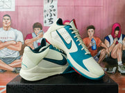 Angled view of the pair highlighting the perforated toe area, teal overlays, red tongue detail and outsole edge.