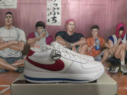 Side profile of a white sneaker with a red Swoosh panel, blue outsole stripe, and padded collar.