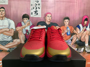 Front view of red Nike basketball sneakers with gold toe panels, red laces, perforated forefoot sections, and black outsoles.