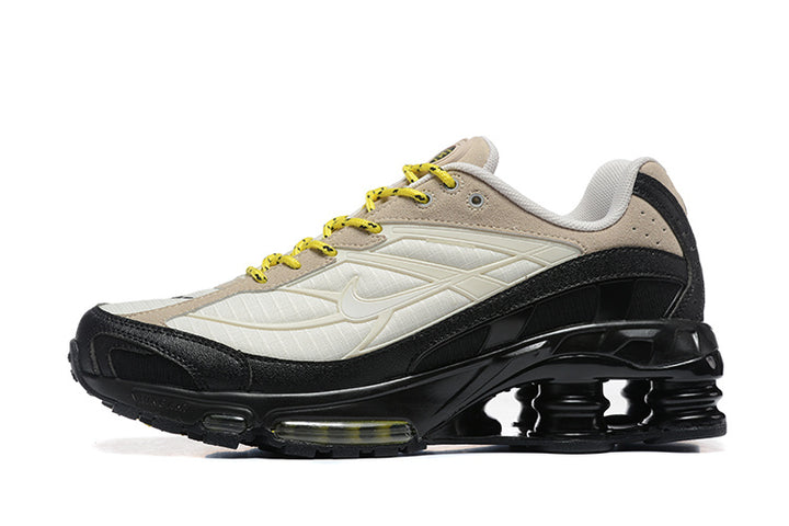 Side view of beige, cream and black Nike Shox Ride 2 sneakers with yellow laces.