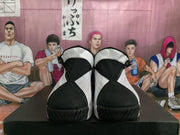 Front view of the white and black sneakers showing black toe panels, black collars, and textured outsoles.