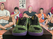 Front view of black and green low-top basketball shoes with black laces and purple outsoles.