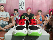Front view showing the black perforated toe panels, red laces, white uppers, and fluorescent green toe and outsole accents.