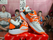 Pair of orange, gray, and white Nike basketball sneakers displayed on a red box