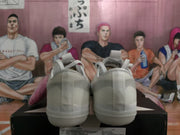 Rear view of the white sneakers showing the textured heel panels, vertical heel strips, and rubber outsoles.