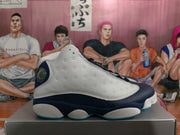 Side profile of a navy and white Jordan basketball sneaker with perforated white panels and a blue outsole edge.