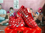 Angled view of the red patterned Nike sneakers displaying the Swoosh, upper graphics, and textured outsole.