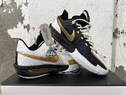 Pair of Nike basketball shoes showing contrasting white-and-gold and black-and-gold sides.