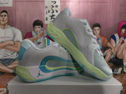 Angled side view of gray Jordan basketball sneakers showing blue and green layered side accents.
