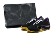 Black and purple basketball shoes with gold-colored outsoles displayed beside a dark shoe box.
