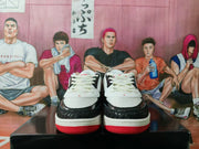 Front view of the pair showing white mesh uppers, black textured toe overlays, white laces, and red outsoles.