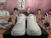 Front view of white Nike basketball sneakers showing textured uppers, white laces and gold tongue branding.
