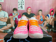 Front view showing the white and pink textured upper with bright orange laces.