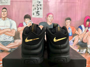 Rear view of the black high-top sneakers with gold-colored heel Swooshes.