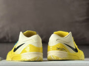 Rear view showing the cream heel collars, yellow heel sections, black graphics, and patterned outsoles.