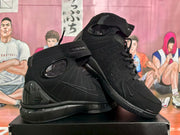 Angled view showing the black sneakers' ankle straps, perforated side panels, tonal Swoosh branding and glossy heel details.