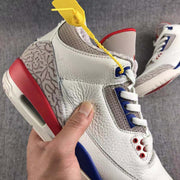 Side close-up showing the white upper, grey perforated collar, blue lace support, red heel section, and patterned panel.