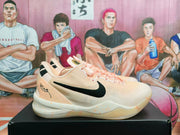 Side view of peach pink Nike basketball sneakers with a black Swoosh, pink laces, and a light midsole.