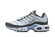 Side view of a white and grey Nike Air Max Plus sneaker.