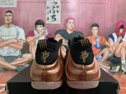 Rear view of rose-gold and black Nike sneakers showing black heels, gold-toned heel emblems, and light outsoles.