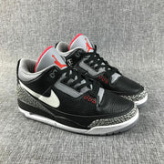 Front three-quarter view of the sneaker pair with black laces, grey perforated panels, red eyelets, and elephant-print toe overlays.