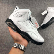 Hand-held side view of one white and black high-top sneaker with perforated panels and sculpted sole.